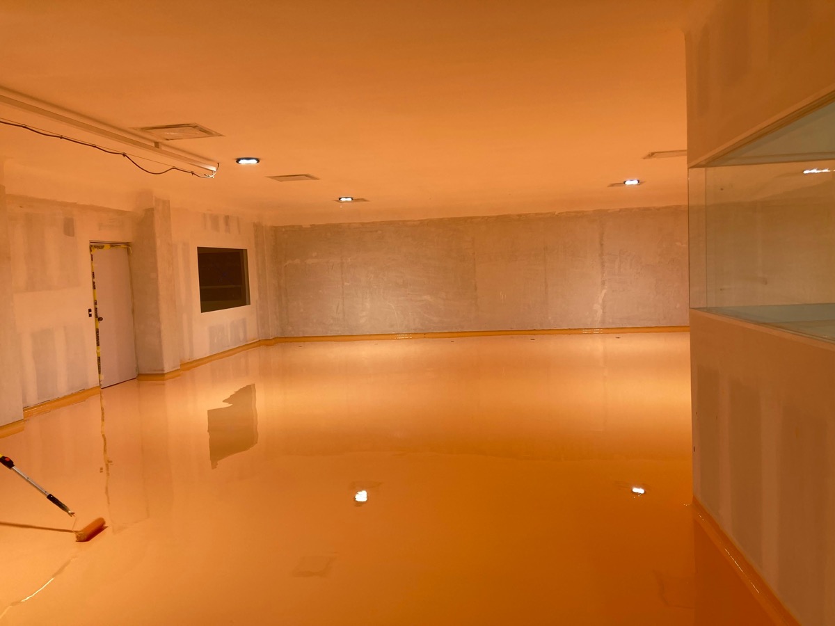 Piso epóxico brillante color naranja en oficina corporativa