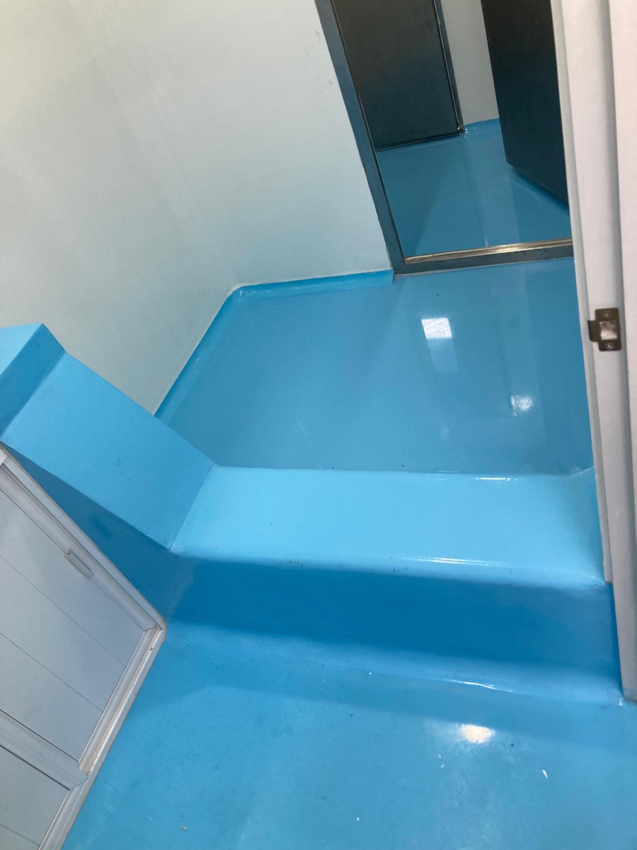 Detalle de media caña sanitaria en piso epóxico azul
